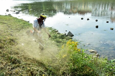 The gardener mowing the grass with a lawn mower