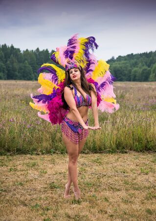 Young girl in bright colorful carnival costume posing outdoors. Sexy brunette preparing for carnavalの写真素材