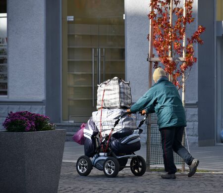 Poor man pulling a cart with bags in the city
