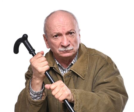 Old angry man threatening with a cane in studio on a white backgroundの写真素材