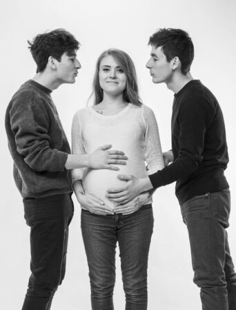 Modern polygamous family with one wife and two husbands. Young pregnant woman posing with two young...