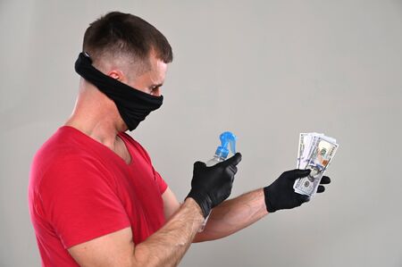 Hygiene and healthcare concept.  Man in protective mask and gloves spraying sanitizing spray on...