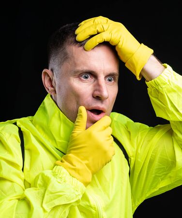 Medicine and healthcare concept. Open-eyed man in yellow protective gloves posing over black...