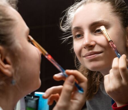 Teenage girl applying make up at home の写真素材