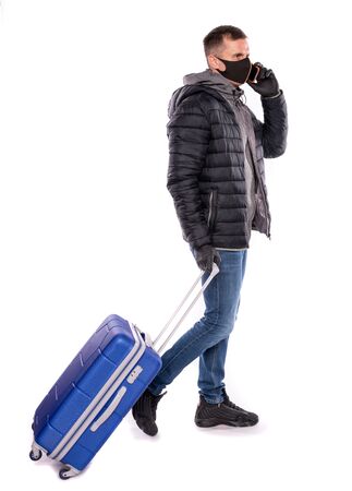 Coronavirus and healthcare concept. Man in protective medical mask with suitcase over white backgroundの写真素材