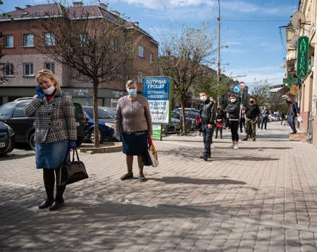 UZHHOROD, UKRAINE - APRIL 10, 2020: Queue to the market during an epidemic in the city of Uzhhorod. Waiting at a safe distance apart from each other during the Coronavirus pandemicのeditorial素材