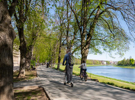 UZHHOROD, UKRAINE - APRIL 18, 2020: People ridingalong the promenade on a spring day in Uzhhorod, Ukraineのeditorial素材