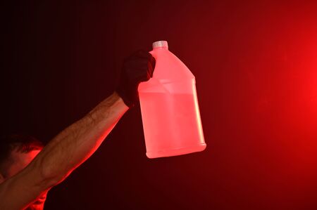 Man in fire holding bottle with water on a red smoky backgroundの写真素材
