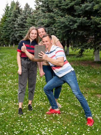 Happy family using tablet PC outdoors in the parkの写真素材