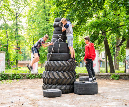 UZHHOROD, UKRAINE - MAY 10, 2020: Ð¡hildren build a pyramid from old tires on the playground in...