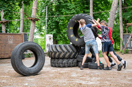 UZHHOROD, UKRAINE - MAY 10, 2020: Ð¡hildren build a pyramid from old tires on the playground in...