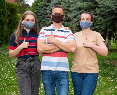 Healthcare concept. Family in protective face masks posing in the parkの写真素材