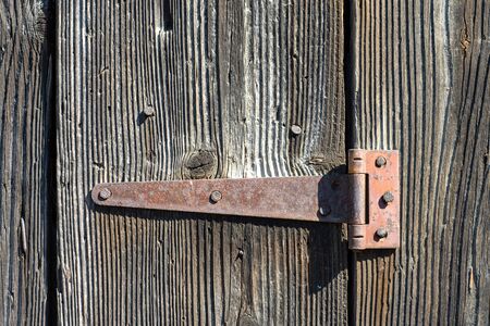 Rusty hinge on an old wooden door, close up