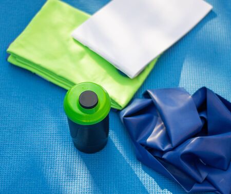 Healthy lifestyle concept. Karemat, towel,  sports bottle  and rubber tape outdoorsの写真素材