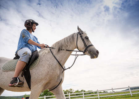 DUBKY, UKRAINE - MAY 23, 2020: Teen girl in helmet learning horseback riding in Dubky, Ukraine