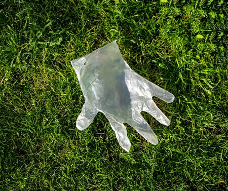 Disposable plastic glove flies lies on the grass during a coronavirus epidemicの写真素材