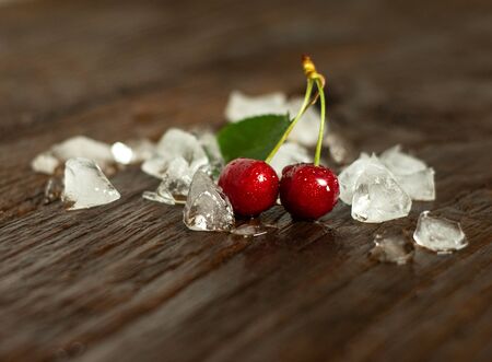Organic fresh cherries and ice on wet wooden backgroundの写真素材