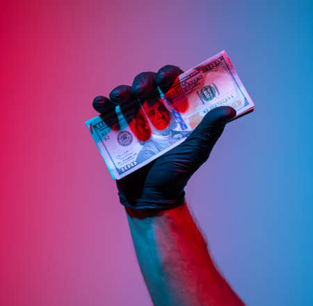 Man in black protective gloves holding pack of dollarsの写真素材