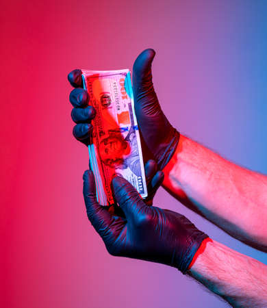 Man in black protective gloves holding pack of dollarsの写真素材