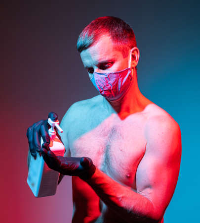 Healthcare and medical concept. Man in protective mask and gloves holding a bottle of hand sanitizerの写真素材