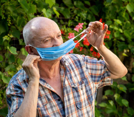 Healthcare and medical concept. Senior man wearing protective mask outdoorsの写真素材