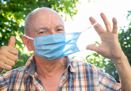 Healthcare and medical concept. Senior man wearing protective mask outdoorsの写真素材