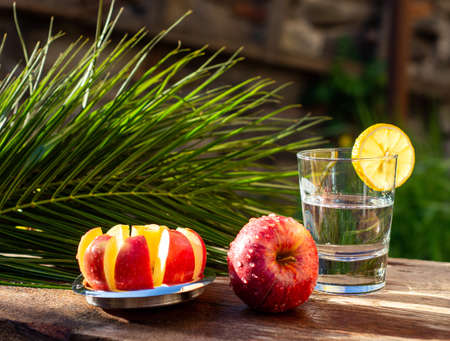Fresh red apples and glass of water on a wooden table in sunny dayの写真素材