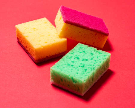 Multicolored sponges for washing dishes on a red backgroundの写真素材