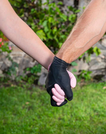 Healthcare concept. Couple in love in protective gloves holding hands outdoorsの写真素材