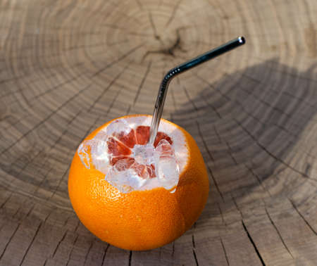 Natural fresh fruit juice concept. Red Grapefruit with metal straw and ice cubes  on a wooden tableの写真素材