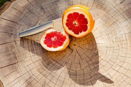 Cutted grapefruit and knife on wooden board. Sliced fresh grapefruit