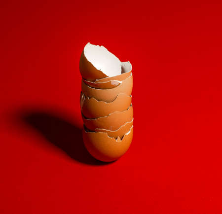 Broken brown eggshells on a red background