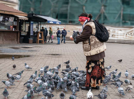Uzhhorod, Ukraine - November 4, 2020: Woman feeding pigeons from hands in Uzhhorod, Ukraine