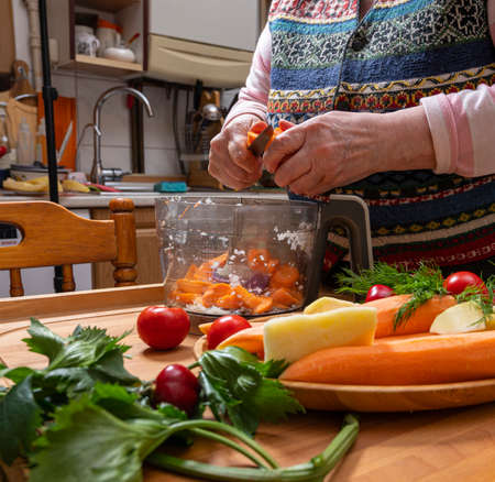 Food and healthy eating concept. Woman chops vegetables in a food processor for s sauceの写真素材