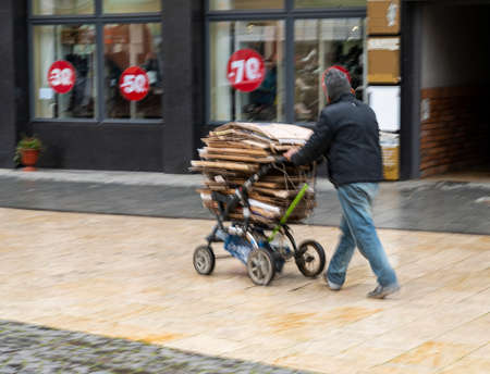 Poor man pulling a cart with cardboard in the city. Intentional motion blur. Defocused imageの写真素材