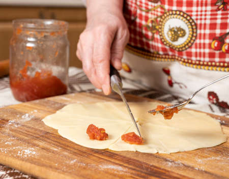 Pastry and baking concept.  Woman preparing homemade rolls with jam  at homeの写真素材