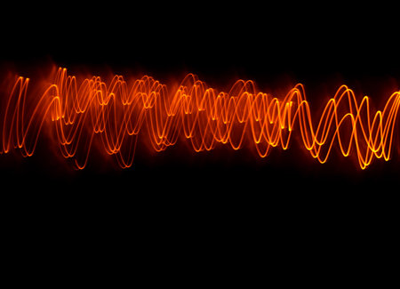 Light wave trail path, vibrant neon gold color in abstract swirls on a black background. Light paintingの写真素材