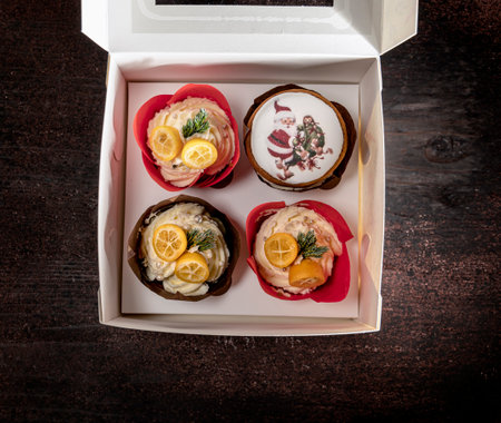 Christmas Dessert. Nicely decorated muffins in a box on a wooden backgroundの写真素材