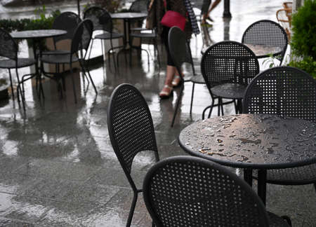 Tables and chairs of a street cafe wet from the rainの写真素材