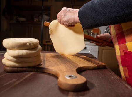 Cooking and home concept. Senior woman preparing tasty pies in the kitchen at homeの写真素材