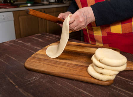 Cooking and home concept. Senior woman preparing tasty pies in the kitchen at homeの写真素材