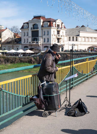 Uzhhorod, Ukraine - April 14,2022: Elderly singer singing on the bridge in Uzhhorod, Ukraine