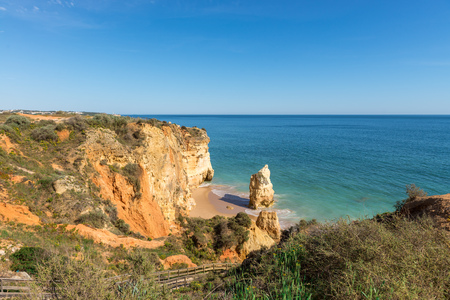 Rocks and footbridge walkway on rock beach and Dona Ana beach in Portimao, Algarve, Portugalの写真素材