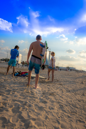 Dubai, United Arab Emirates - December 2, 2014 :  Group of people getting ready to surf in Jumeirah beach during a sunny day. The famous and luxury hotel Burj Al Arab is located near this beach.のeditorial素材
