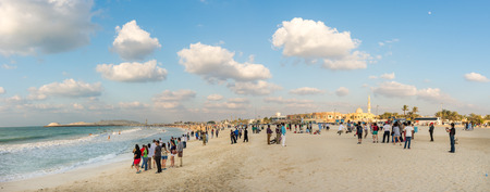 Dubai, United Arab Emirates - December 2, 2014: Many tourists on the Jumeirah Marina beach during a sunny day. The famous and luxury hotel Burj Al Arab is located near this beach.のeditorial素材