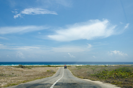 Aruba, Caribbean - September 26, 2012: Dry and arid desert landscape with road and native plants in Aruba Island at the Caribbean seaのeditorial素材