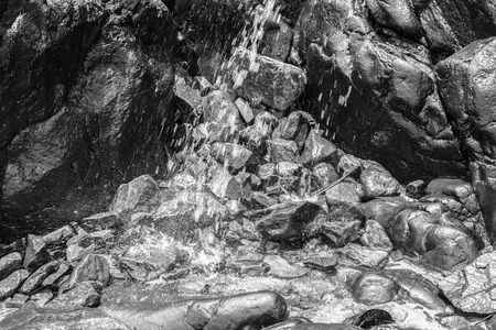 Small waterfall among rocks and stones in moss by the beachの写真素材