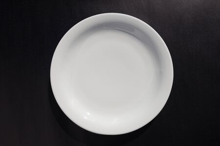 White shallow ceramic rounded plate on black backgroundの写真素材