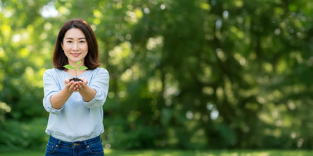 An Asian woman Holding a Small Growing Plant. Hope and Sustainability.の素材