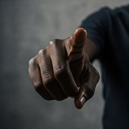 Close-up of a Black man's hand pointing directly at the camera with focus on the finger against a dark backgroundの素材